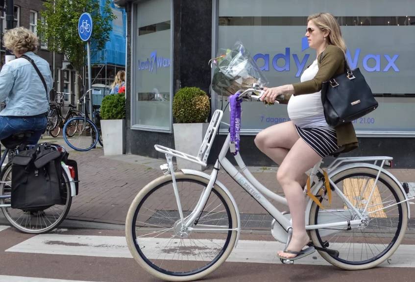 An unhelmeted Dutch pregnant female cycl